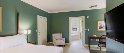 A hotel room with a bed, a chair, a desk, and a television.