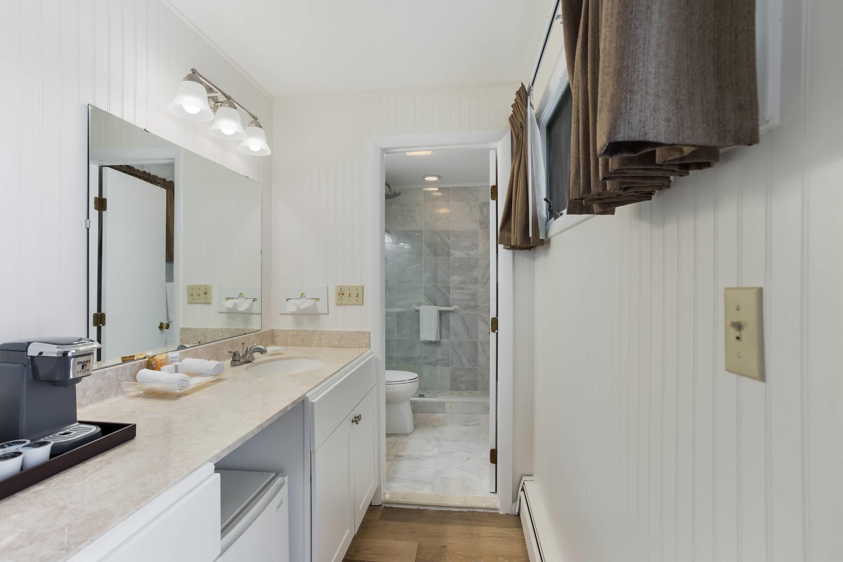 A modern bathroom with a large mirror, dual sinks, and a shower area.