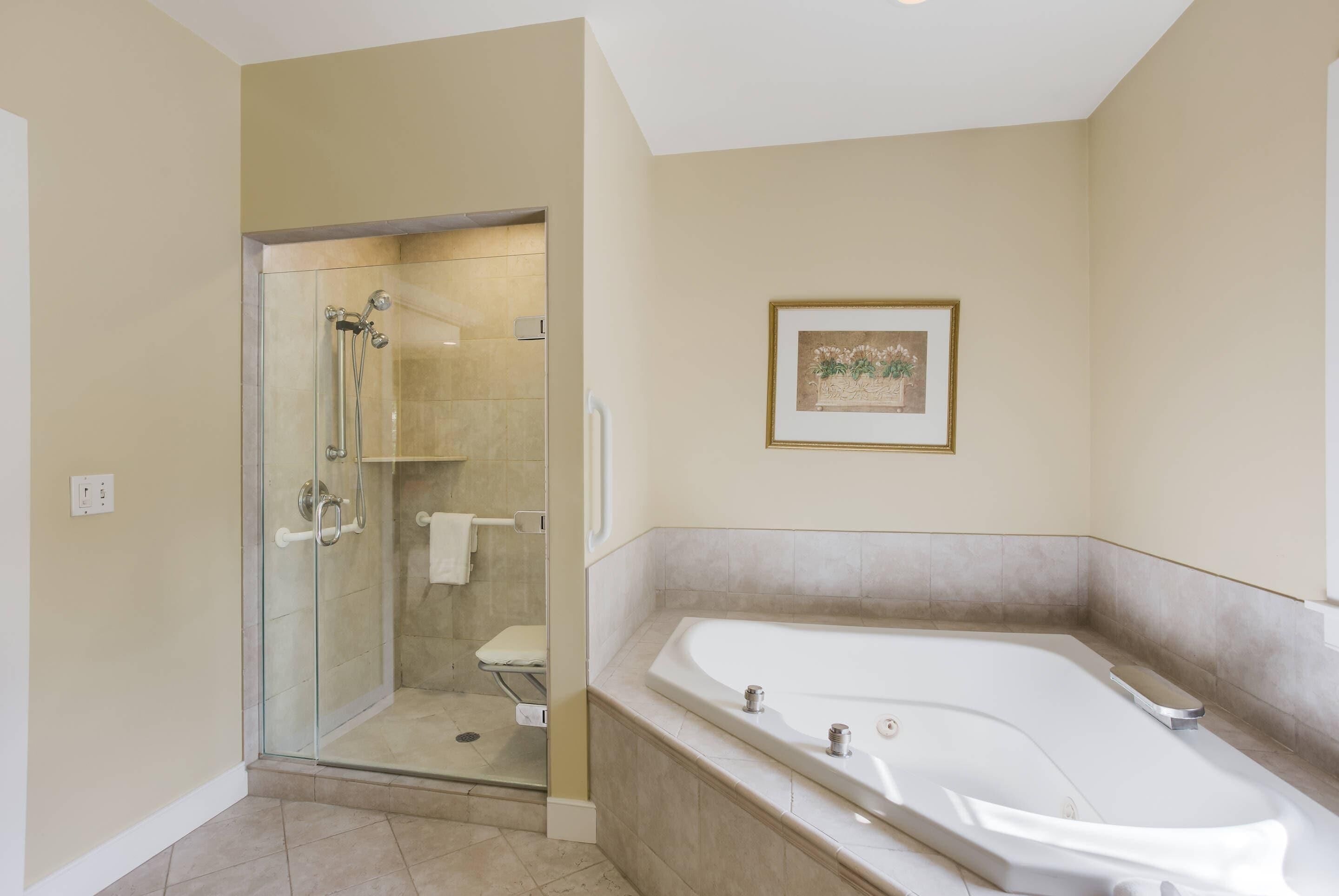 A modern bathroom with a glass-enclosed shower, a large bathtub, and a framed picture on the wall.