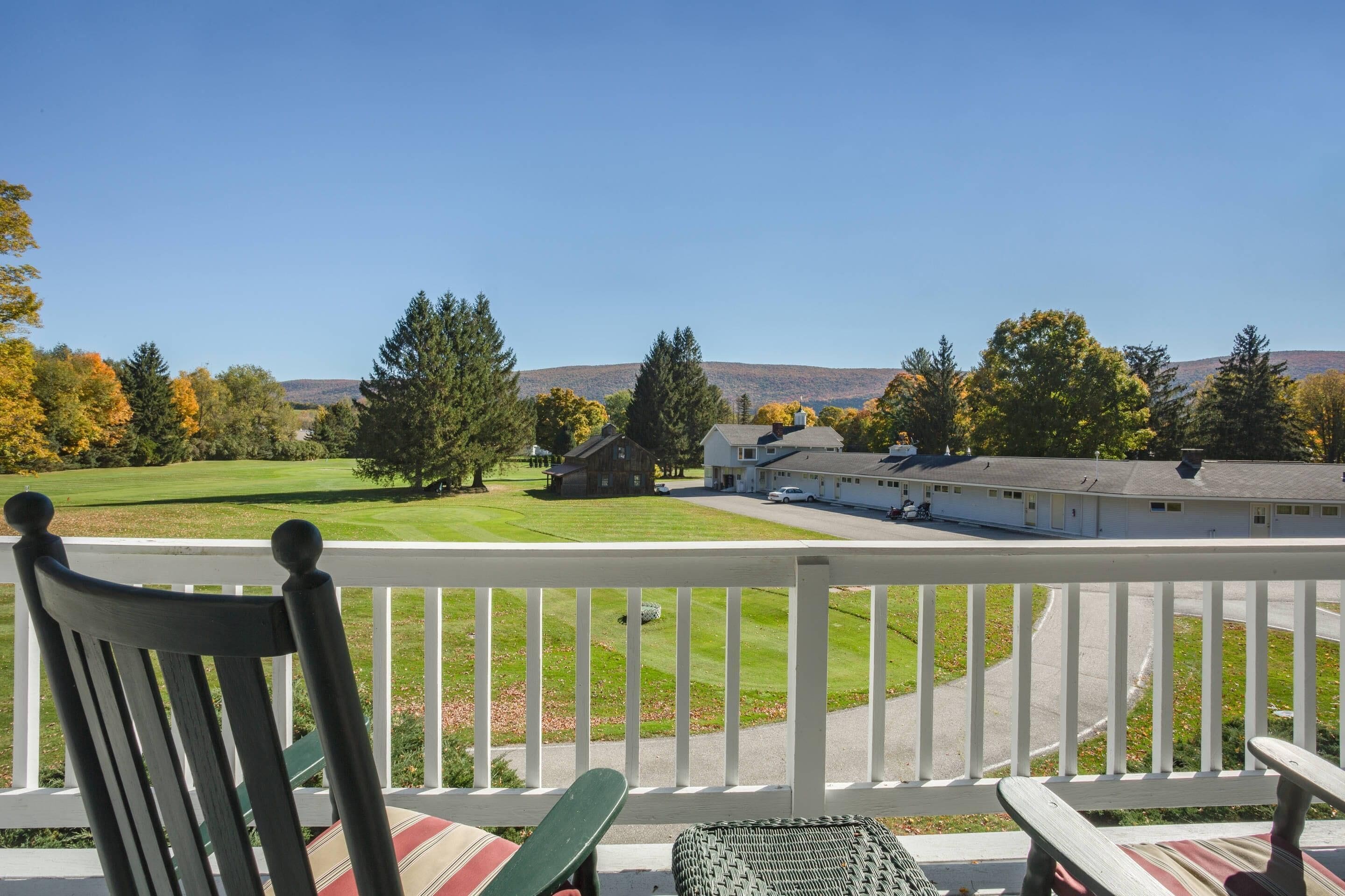 Eine Veranda mit Blick auf einen Golfplatz, ein Gebäude und Bäume.