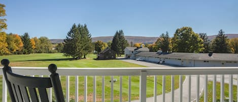Eine Veranda mit Blick auf einen Golfplatz, ein Gebäude und Bäume.