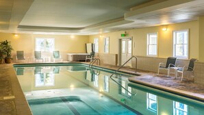An indoor swimming pool with clear water, surrounded by chairs and a bench. - The Palmer House Resort, an Ascend Collection Hotel (Manchester Center)