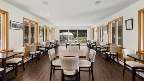 A spacious dining area with multiple tables and chairs, large windows, and a view of the outdoors. - The Palmer House Resort, an Ascend Collection Hotel (Manchester Center)