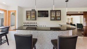 A modern kitchen with a curved island, bar stools, wine bottles, and a television. - The Palmer House Resort, an Ascend Collection Hotel (Manchester Center)