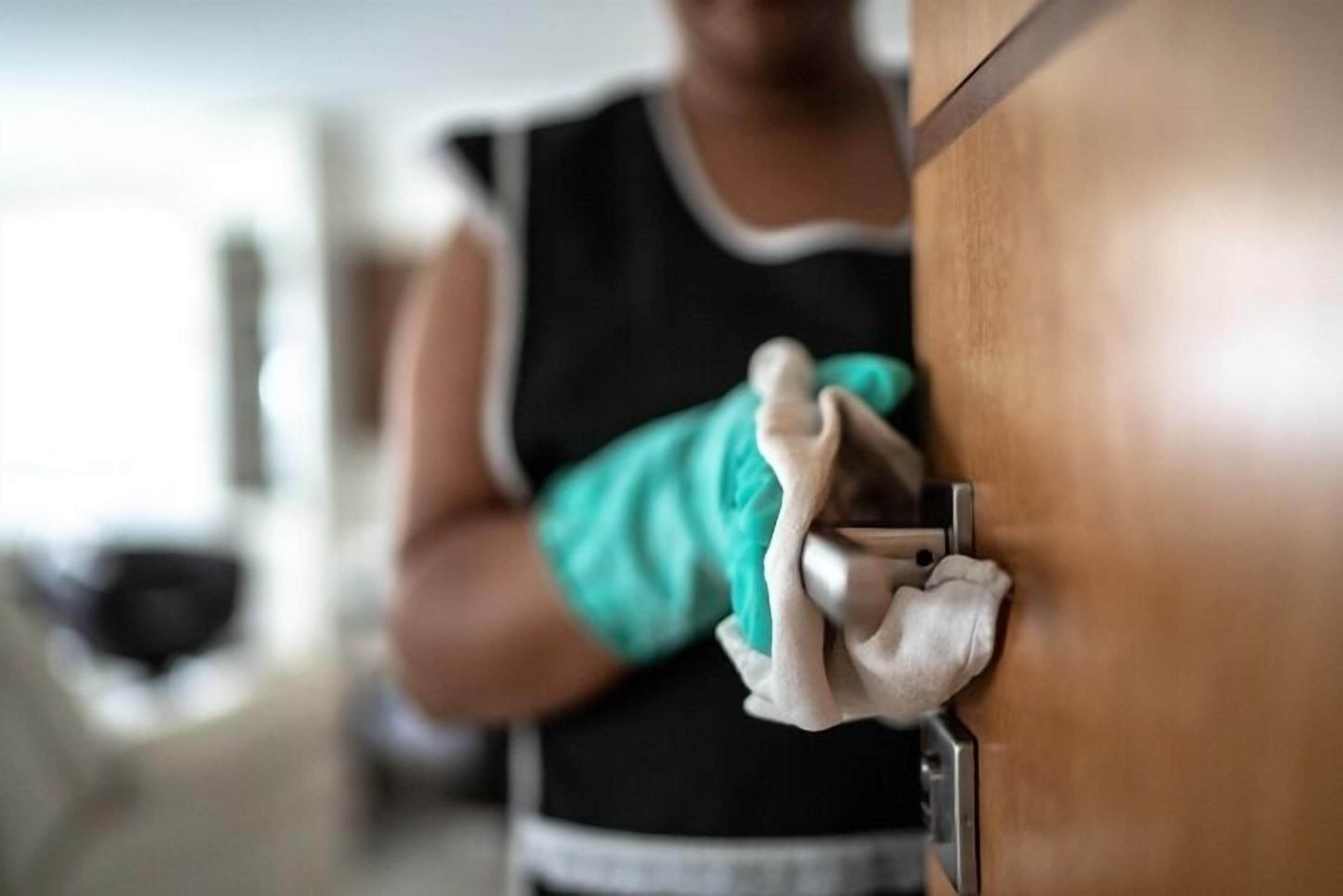 A person cleaning a wooden door with a cloth.