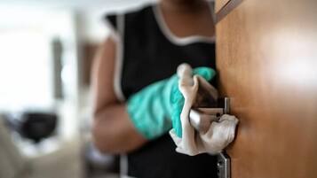 Une personne nettoie une porte en bois avec un chiffon.