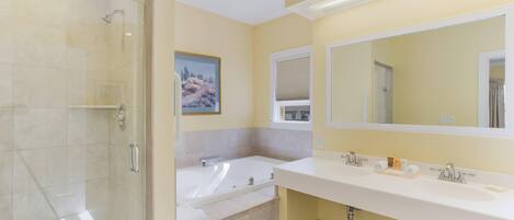 A bathroom with a glass-enclosed shower, a bathtub, and a large mirror above a double sink.