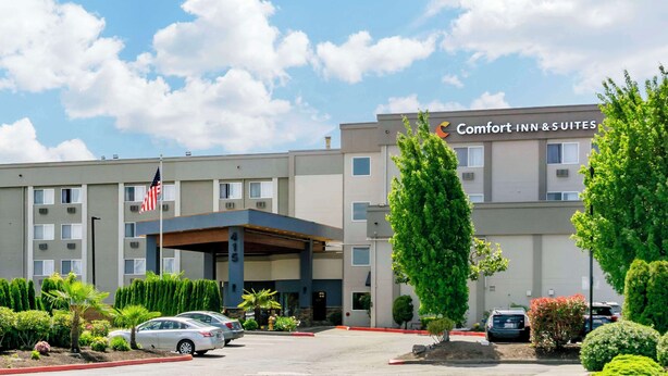 A Comfort Inn & Suites building with a covered entrance, flag, and parking lot. - Comfort Inn & Suites Pacific - Auburn (Pacific)