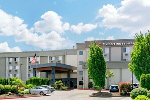 A Comfort Inn & Suites building with a covered entrance, flag, and parking lot. - Comfort Inn & Suites Pacific - Auburn (Pacific)