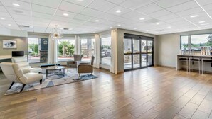 A spacious lobby with a modern design, featuring a seating area with a sofa and chairs, a coffee table, and a large window offering a view of the outside. - Comfort Inn & Suites Pacific - Auburn (Pacific)