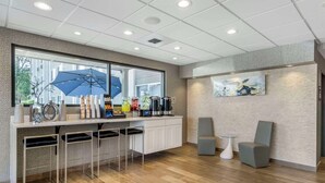 A modern bar area with a large window, bar stools, and a seating area with two chairs. - Comfort Inn & Suites Pacific - Auburn (Pacific)
