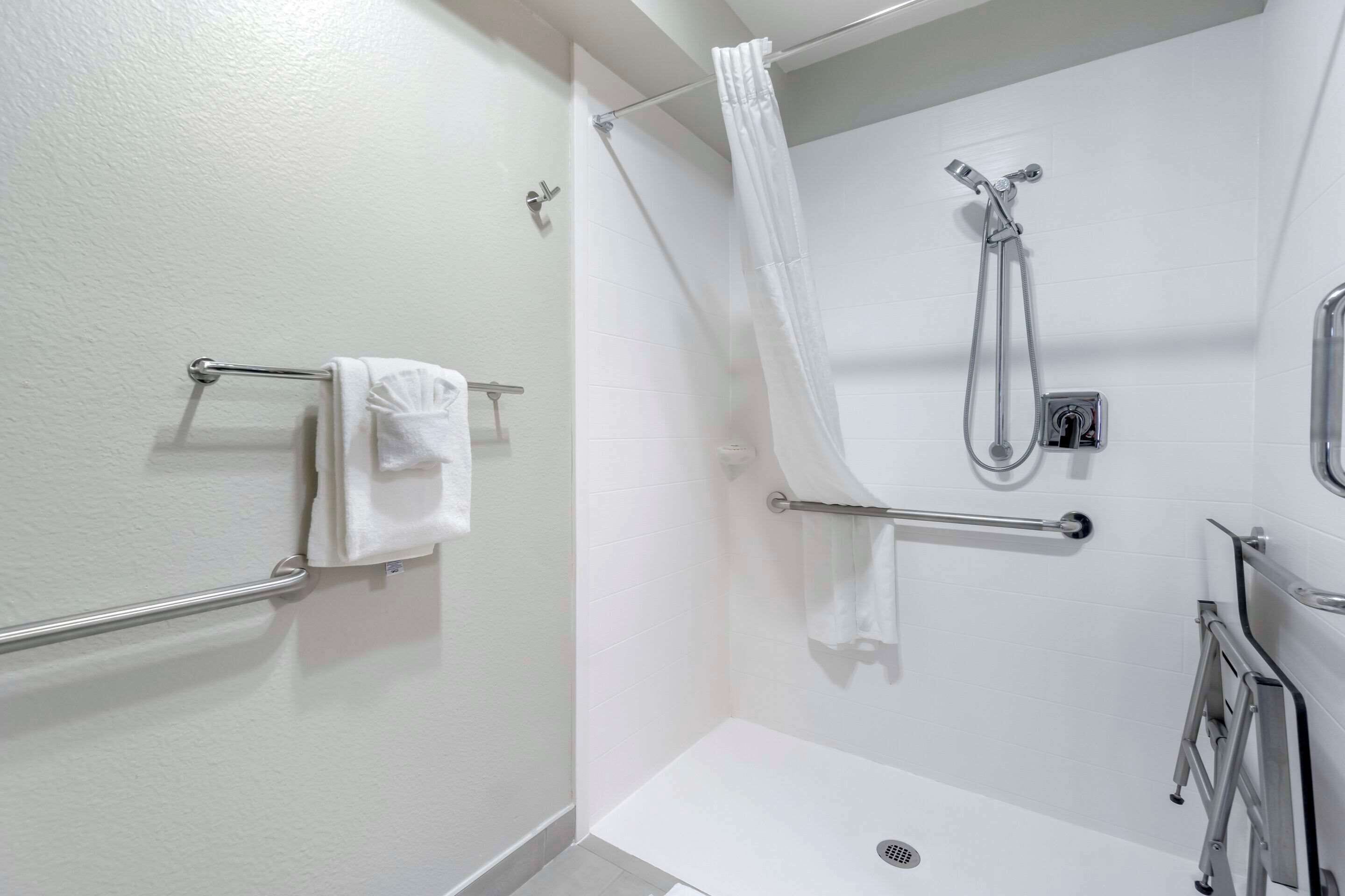 Une salle de bain moderne équipée d’une douche, de barres d’appui et d’un porte-serviettes.
