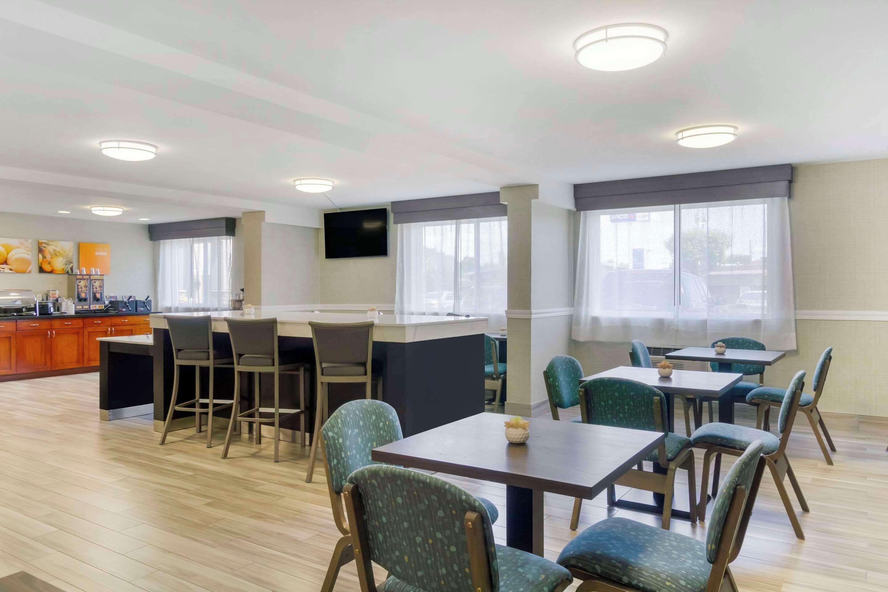 Een restaurantgedeelte van een hotel met een bar, meerdere tafels en stoelen.