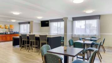 Een restaurantgedeelte van een hotel met een bar, meerdere tafels en stoelen.