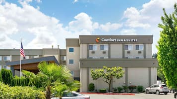 Ein Hotel mit einem Schild, auf dem "Comfort Inn & Suites" steht, und einer Fahnenmast mit der US-amerikanischen Flagge.