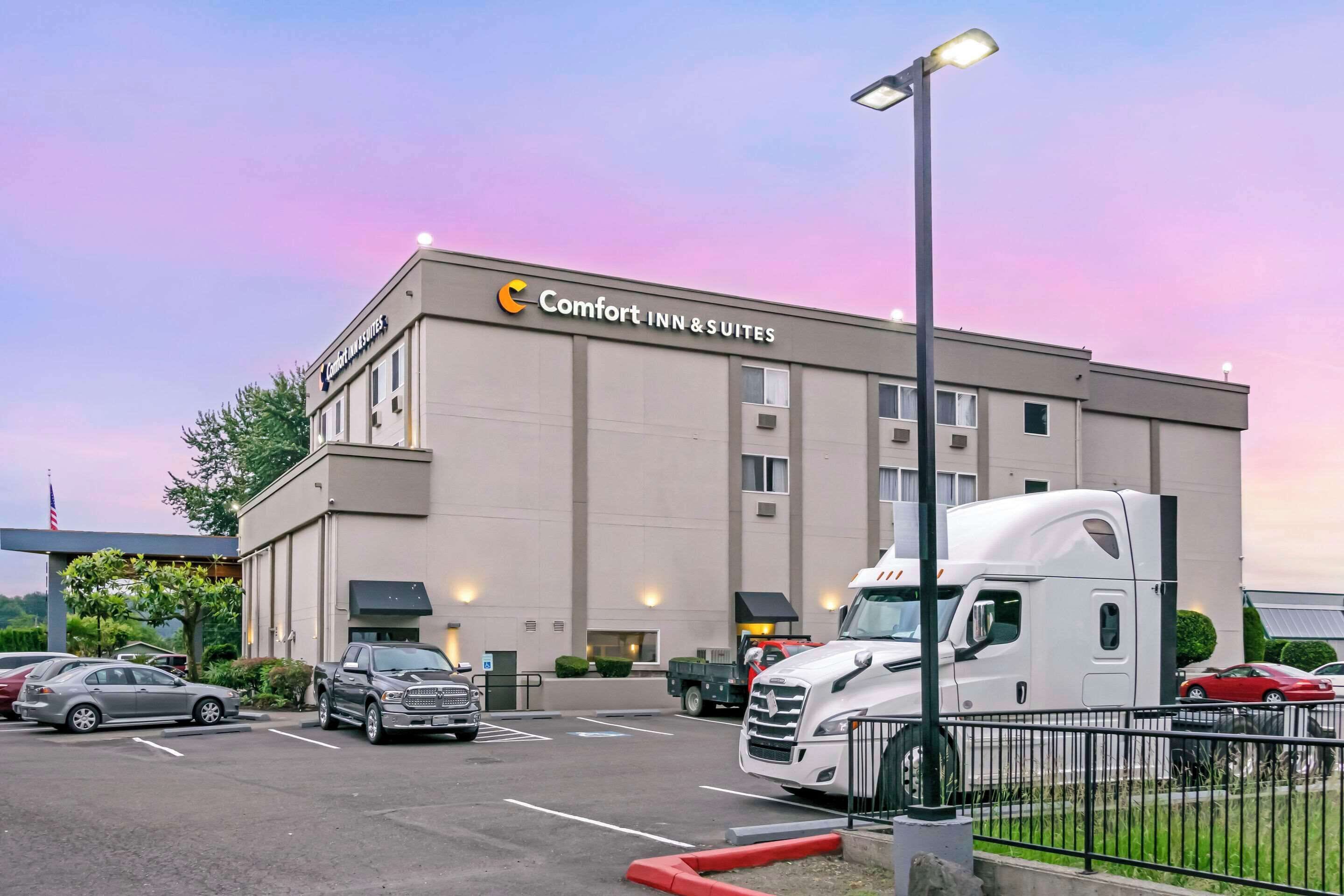 A Comfort Inn & Suites building with a parking lot, a white truck, and a red car.