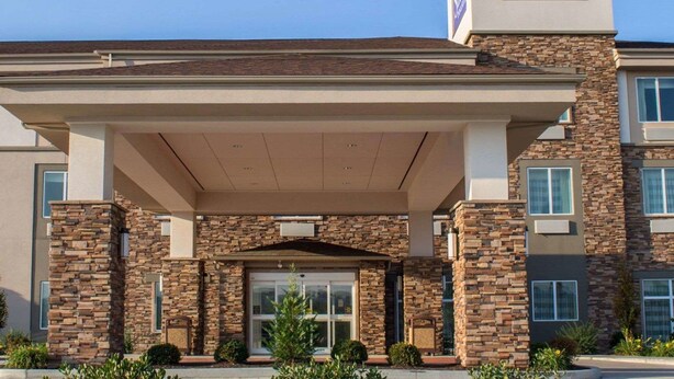 A Sleep Inn & Suites building with a stone facade, a covered entrance, and a clear blue sky.