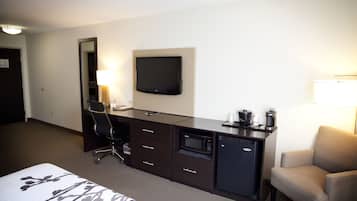 Une chambre d’hôtel équipée d’un lit, d’un bureau avec un téléviseur à écran plat, d’un four à micro-ondes, d’une machine à café, d’une chaise et d’une lampe.