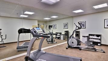 Une salle de sport équipée de tapis de course, de vélos elliptiques et d’un vélo d’appartement.