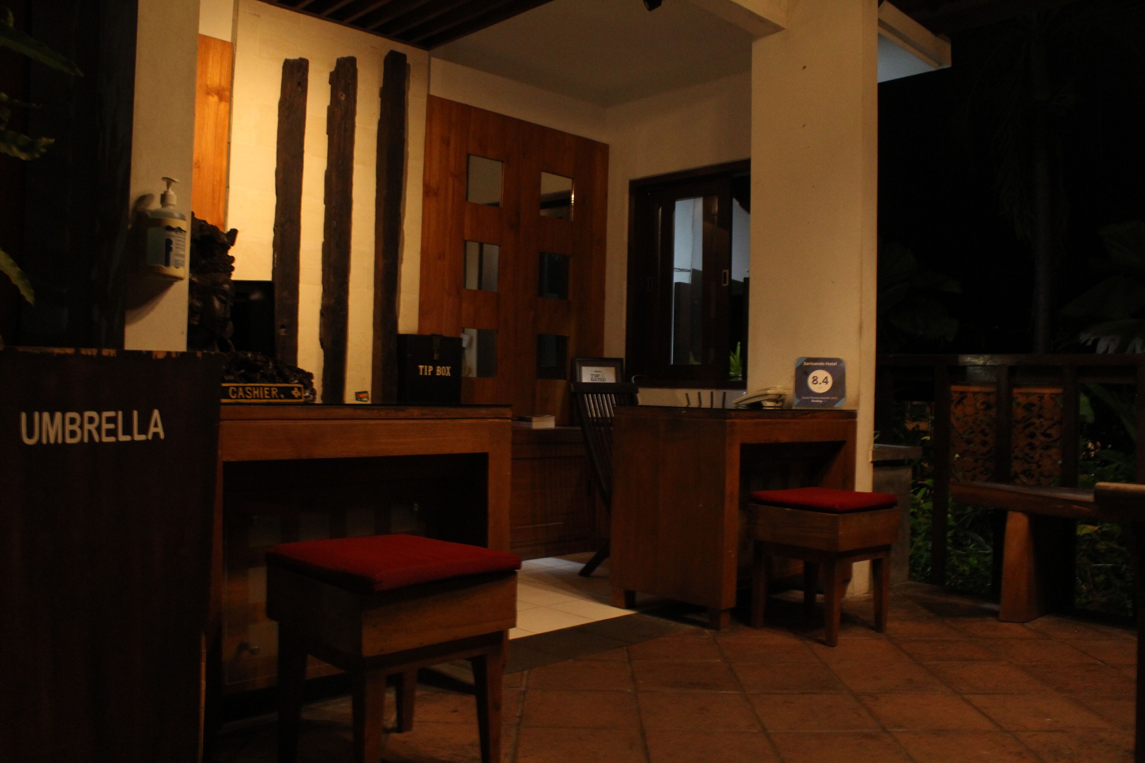Una habitación poco iluminada con mobiliario de madera, una caja registradora y un cartel que dice 'CASHIER'.