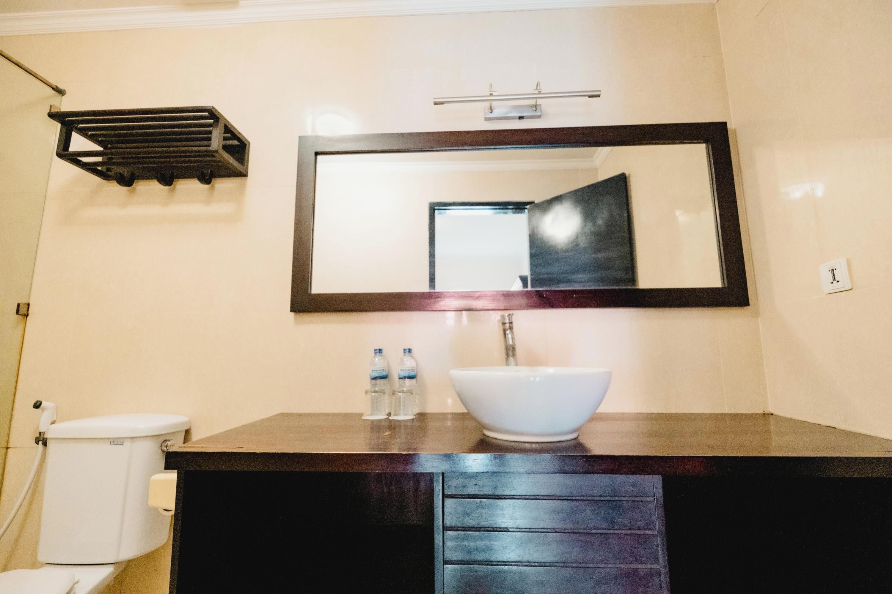 A bathroom with a white sink, dark wooden vanity, and a large mirror.