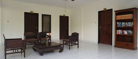 A spacious living room with a ceiling fan, a wooden bookshelf, and a white brick wall.
