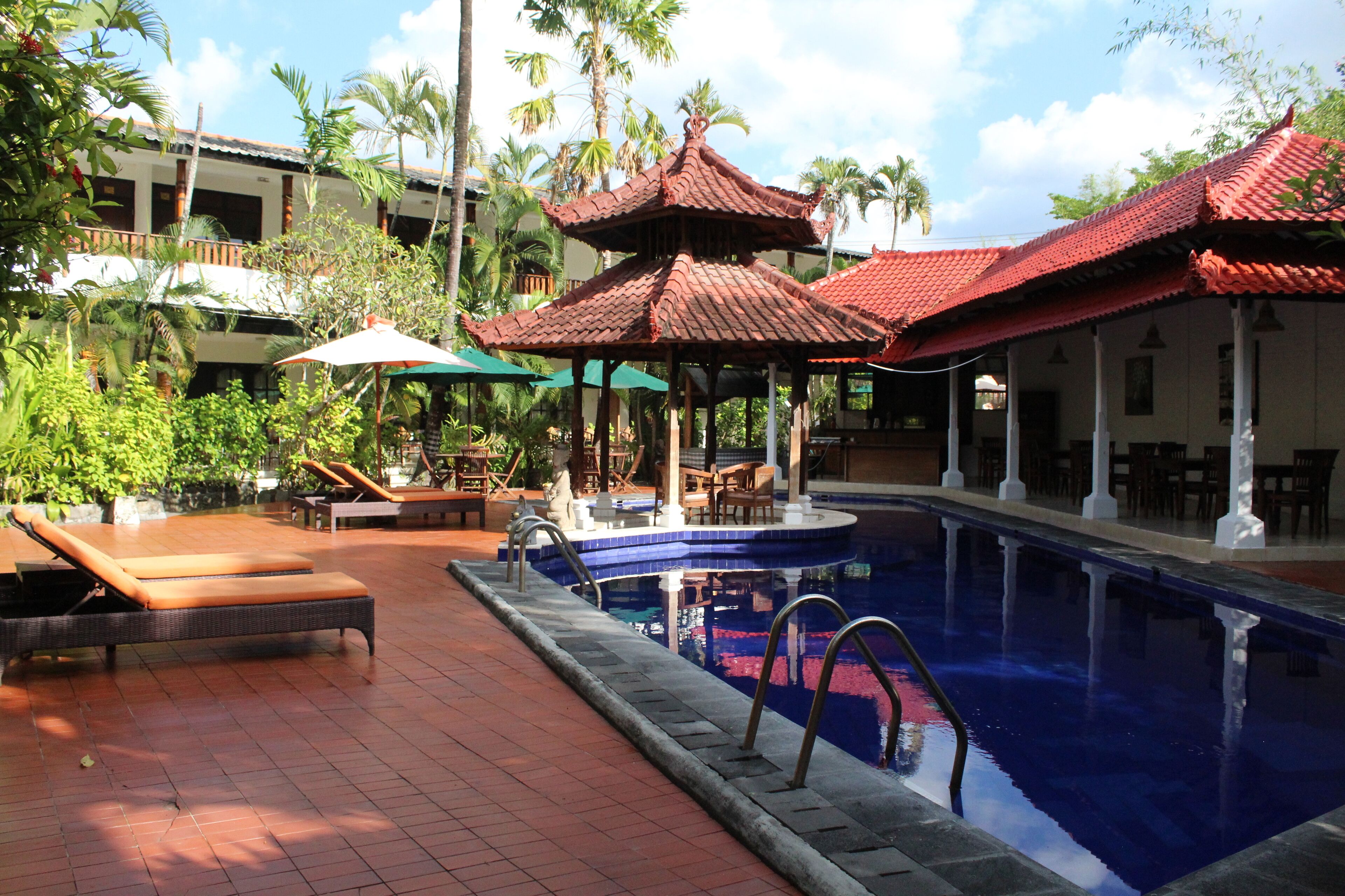 A pool area with lounge chairs, a small pool, and traditional-style umbrellas.