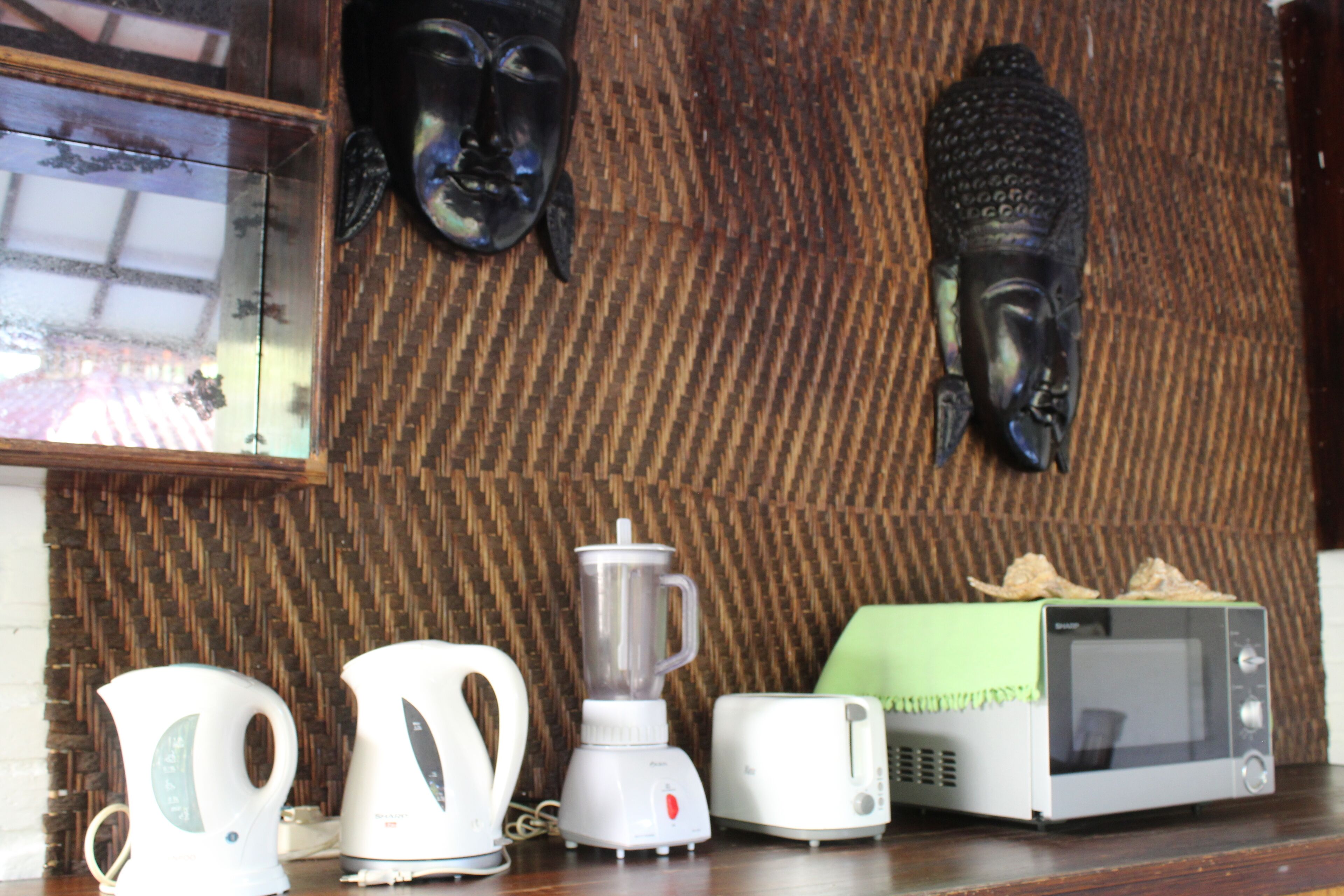 A kitchen with a blender, kettle, toaster, and microwave on a wooden countertop.