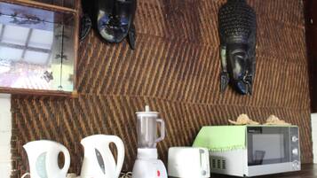 A kitchen with a blender, kettle, toaster, and microwave on a wooden countertop.