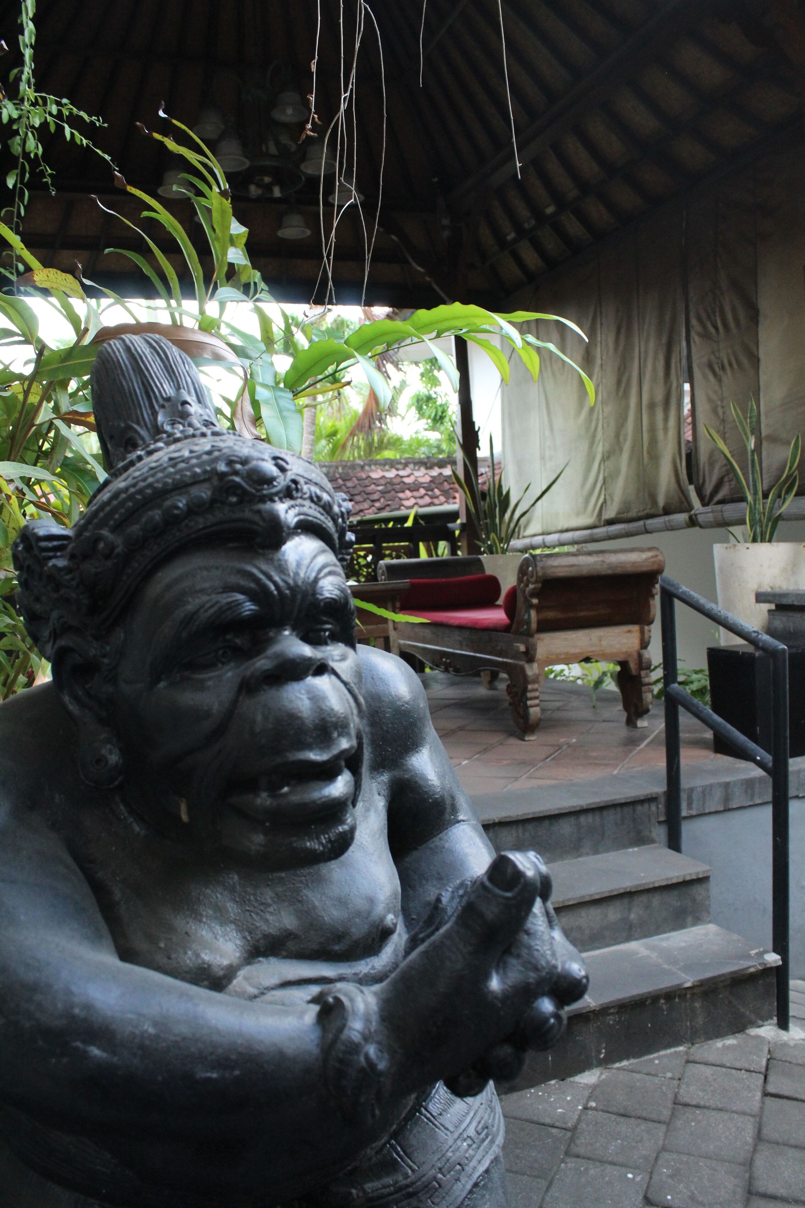 A statue of a seated figure with a large head and hands clasped in front.