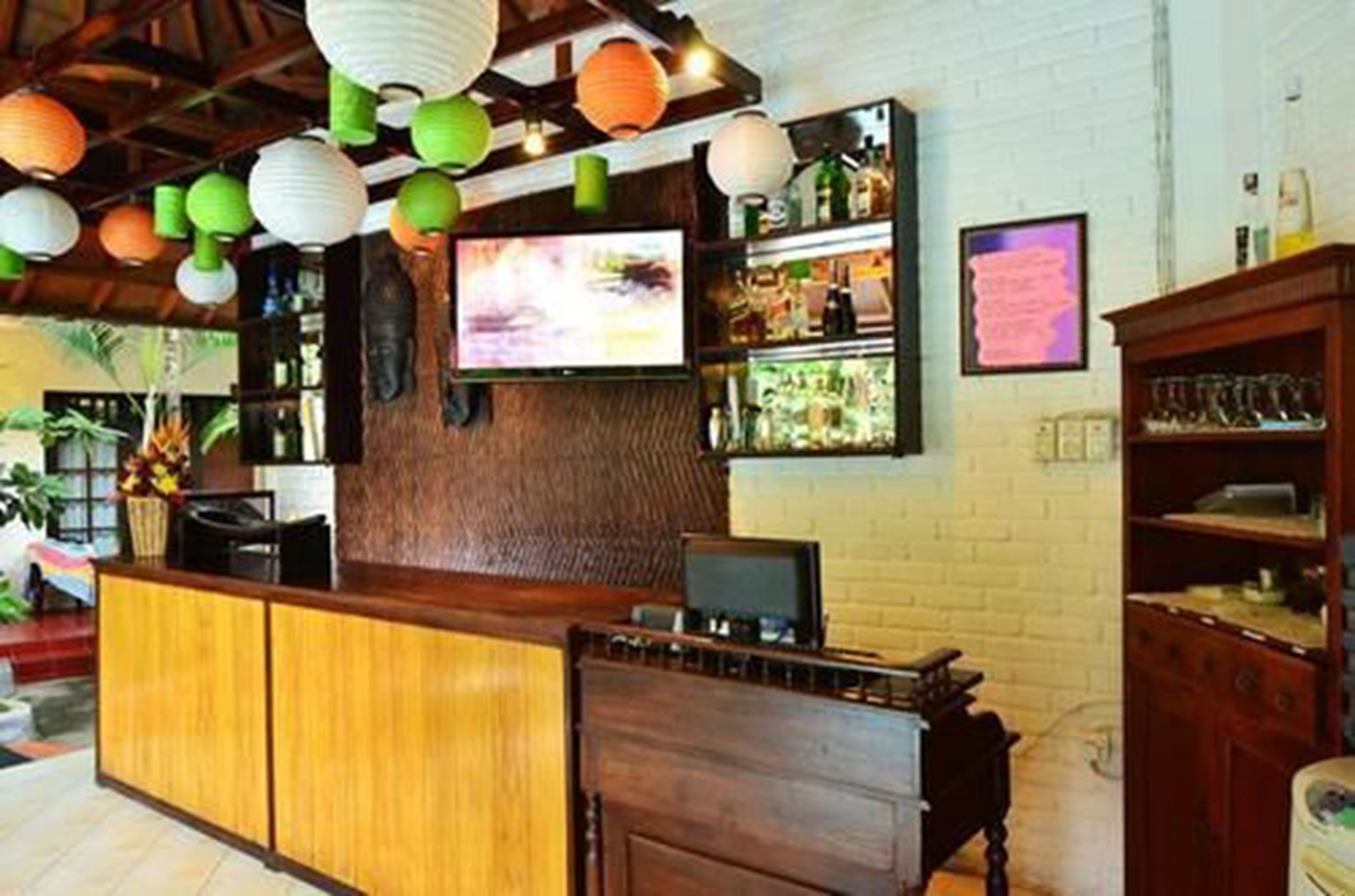 A bar area with wooden cabinets, a television, and a refrigerator.