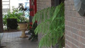 A brick building with a potted plant and a large urn on the ground. - Bidgee Motor Inn (Hay)