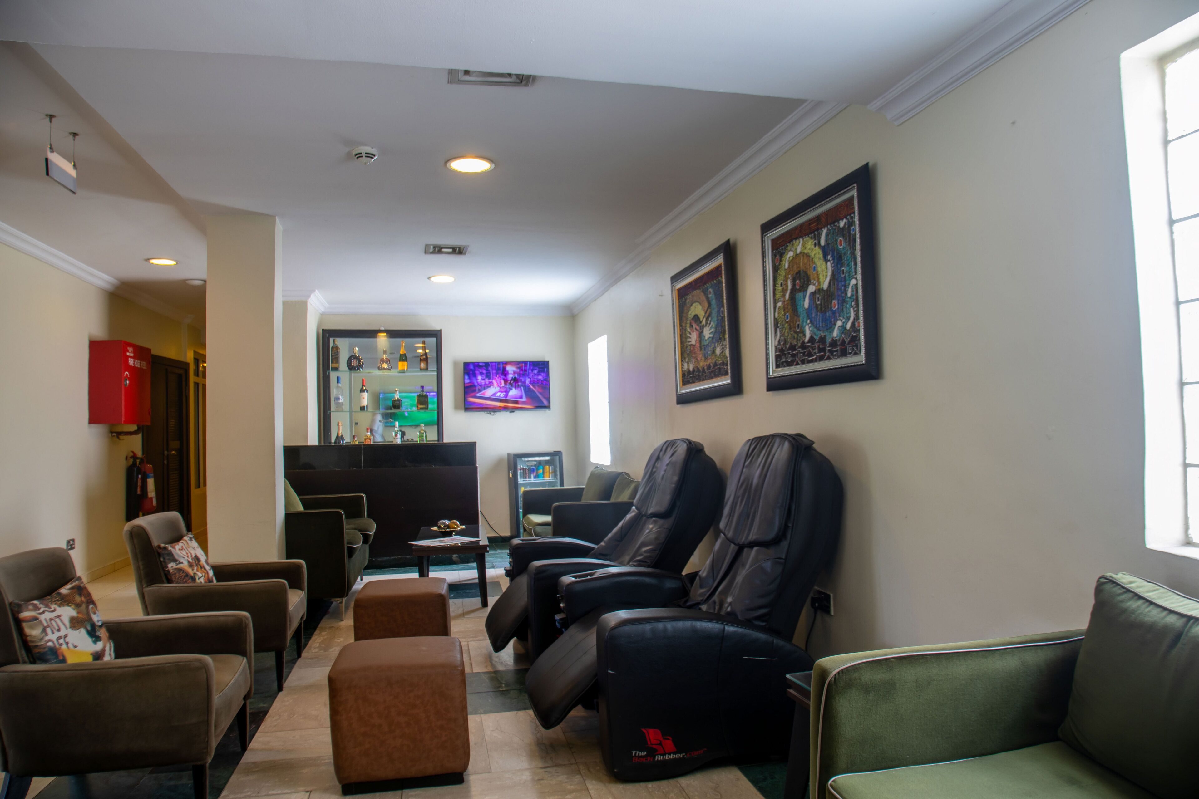 A hotel lobby with leather chairs, a reception desk, and artwork on the walls.