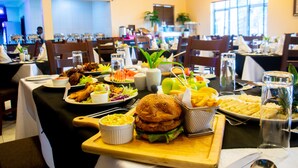 Un comedor con varias mesas dispuestas para comidas, que incluye una variedad de platos y una hamburguesa grande como pieza central.