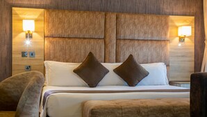 Una habitación de hotel con una cama grande, dos lámparas de noche, una mesita de noche y una silla.