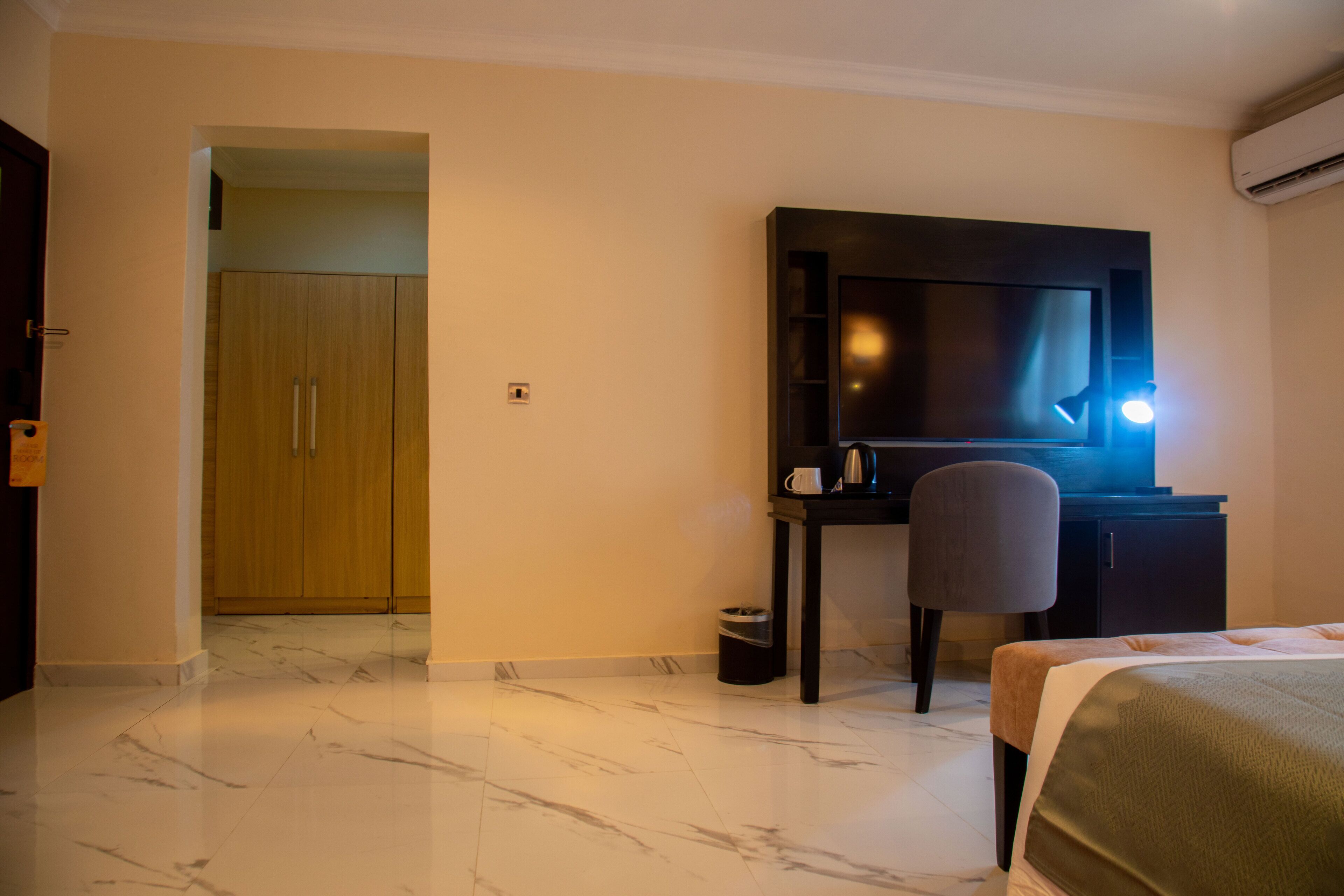 Una habitación de hotel con cama, escritorio, silla, televisor y armario.
