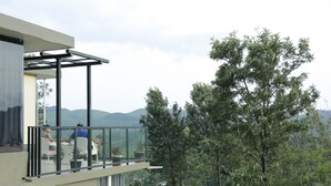 Un edificio moderno con balcón de vidrio que da a un paisaje exuberante.