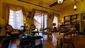 Un salon chaleureux avec un piano, des fauteuils, une table basse et une cheminée.