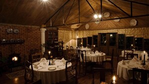 Un restaurant avec des tables rondes disposées pour le service, un mur en briques et un plafond en bois.