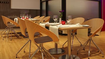 Un comedor con sillas y mesas de madera, cada juego con cubiertos y vasos.