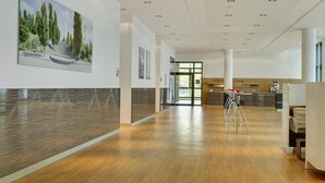 A modern hotel lobby with a wooden floor, a reception desk, and a large painting on the wall. - IntercityHotel Berlin Hauptbahnhof (Berlin)