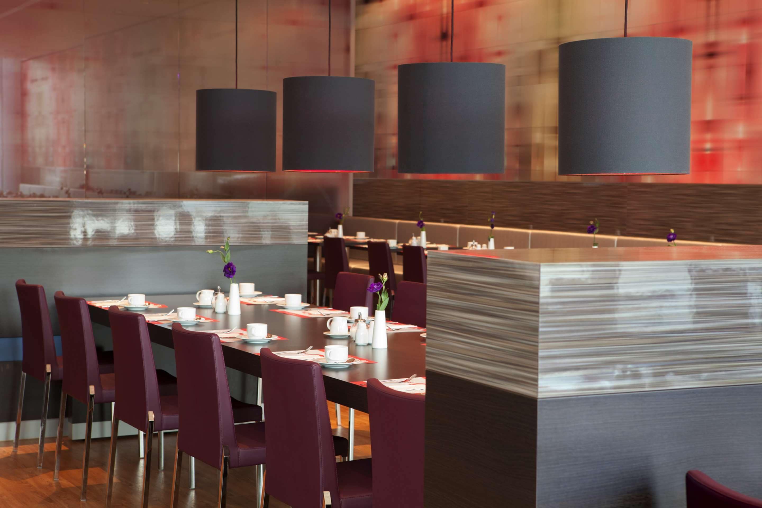 A modern dining area with a long table set for a meal, surrounded by chairs.