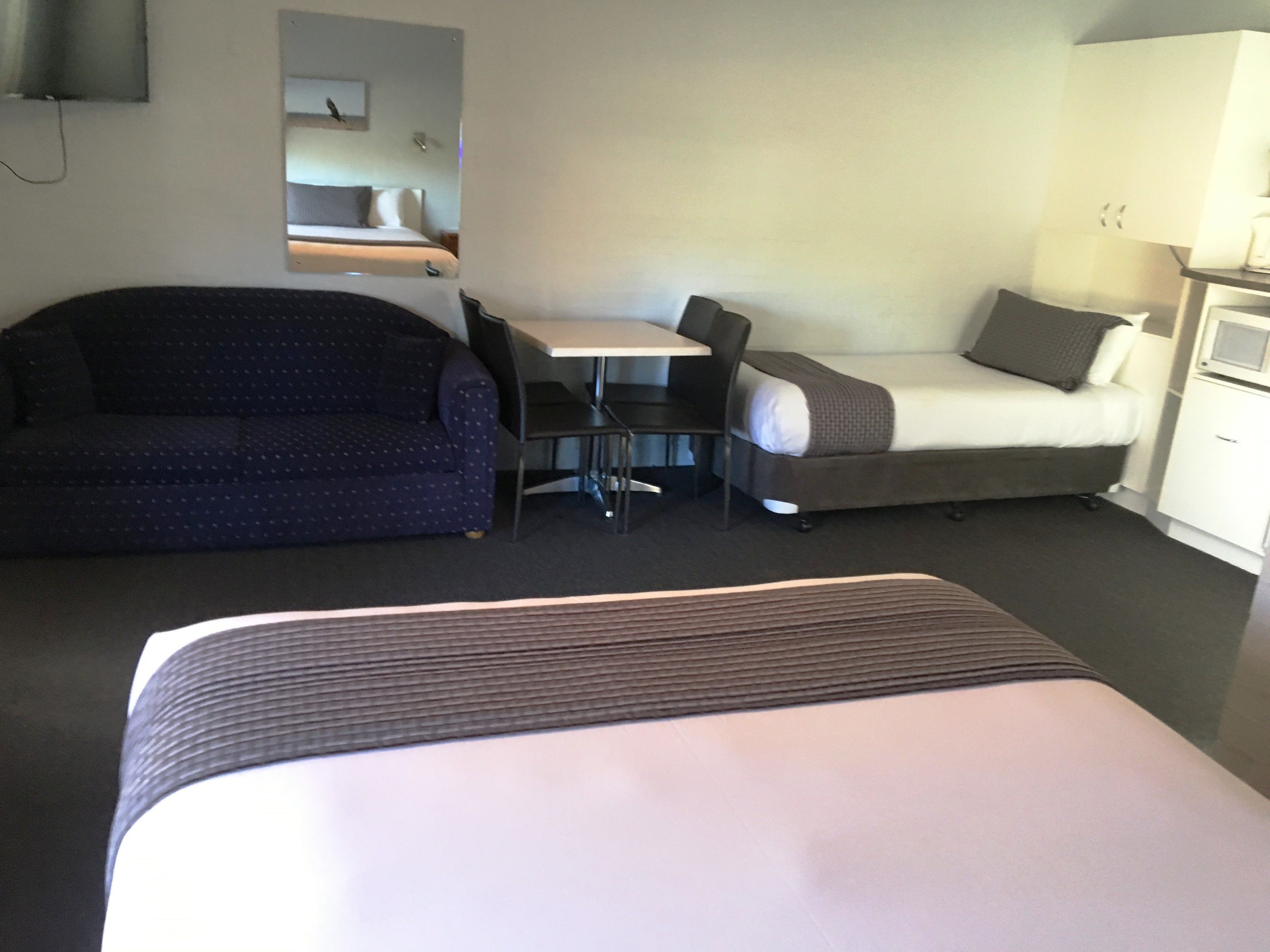 A hotel room with a bed, a sofa, a desk, and a chair.