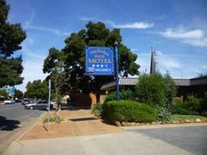 Un motel con insegna blu, un parcheggio e un edificio con tetto spiovente.