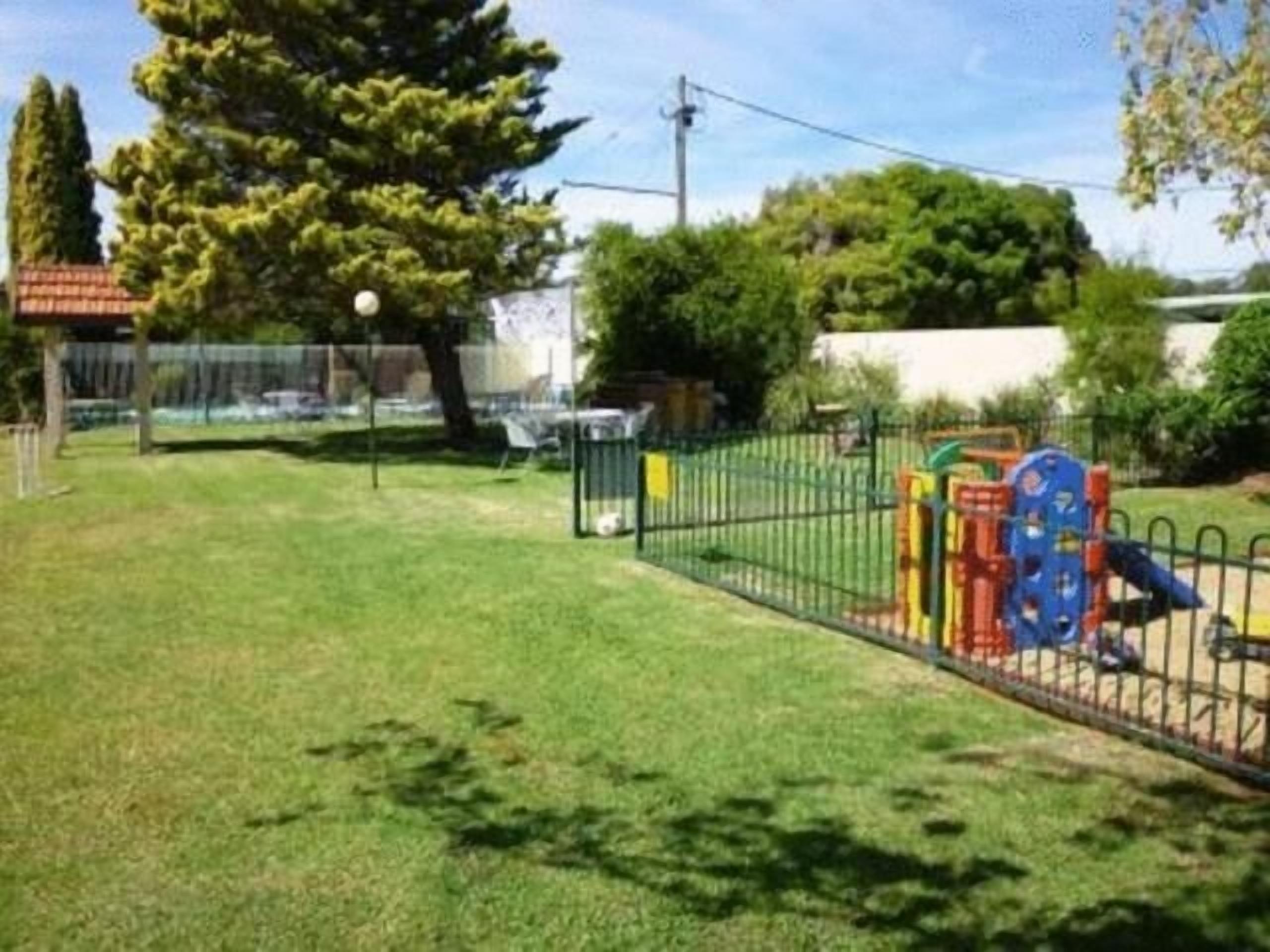 A fenced outdoor area with a playground, including a slide and climbing structures.