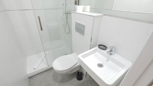 A modern bathroom with a glass shower enclosure, a white toilet, and a sink with a drain. - Pensión MYD La Estrella (Madrid)