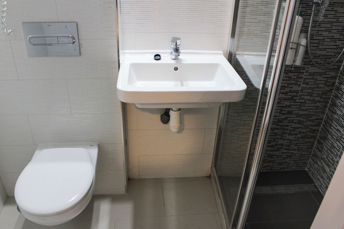 A bathroom with a white sink, toilet, and shower.