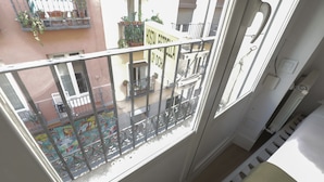 A balcony with a metal railing, a window, and a view of a building with a sign that reads "HOSTAL ESTRELLA 2º DCH." - Pensión MYD La Estrella (Madrid)