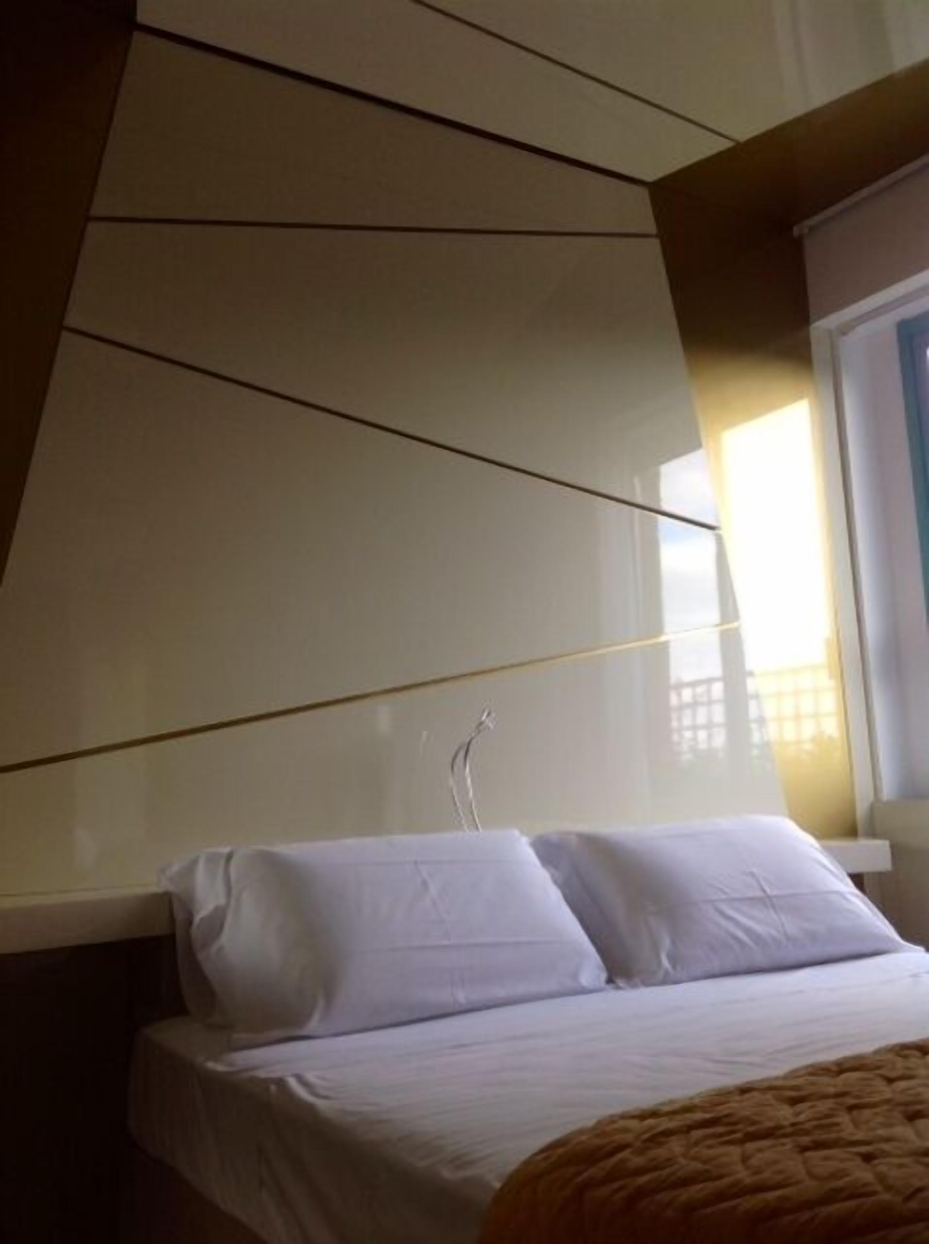 A bedroom with a bed, white pillows, and a window with curtains.