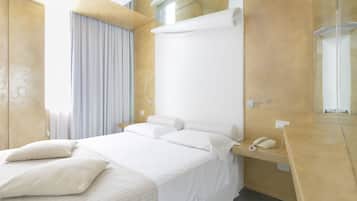 A modern hotel room with a large bed, a bedside telephone, and a mirror on the wall.